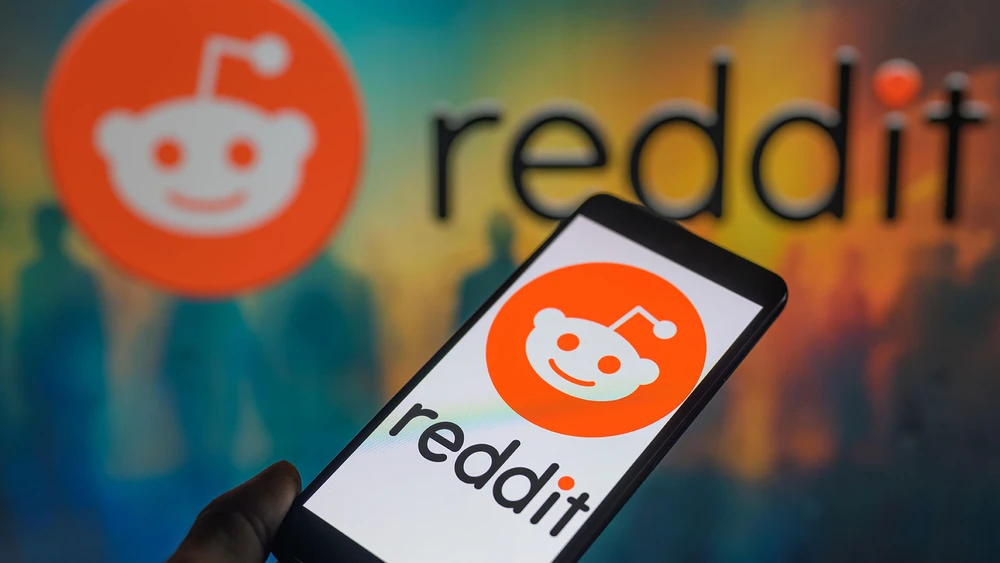 reddit Logo auf Smartphone vor buntem Hintergrund mit reddit Logo