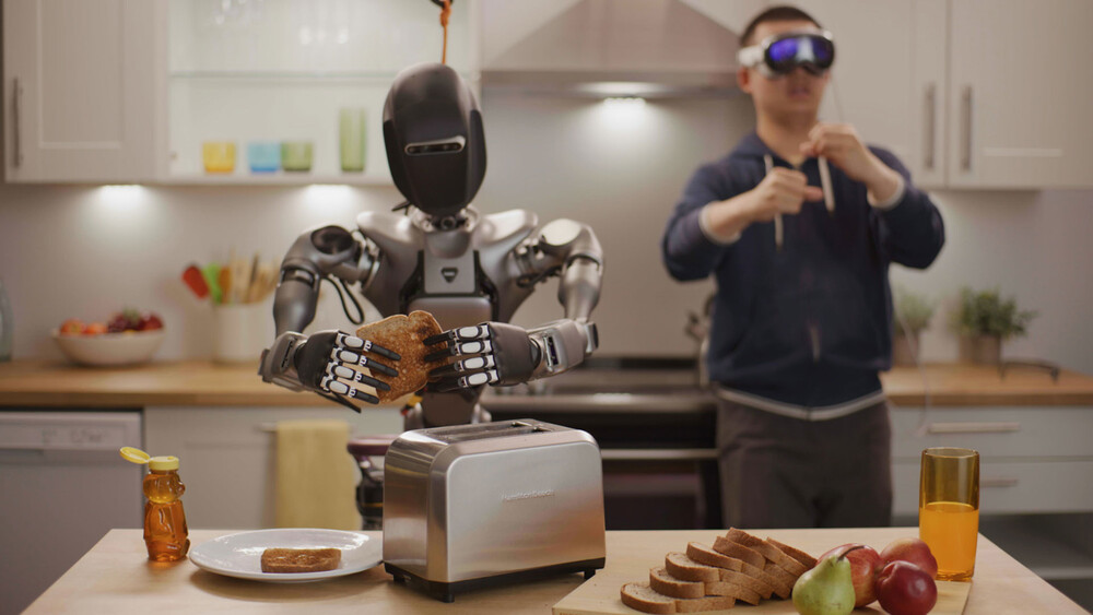 Een humanoïde robot in een keuken wordt bestuurd door een man met een VR-bril terwijl hij toast klaarmaakt