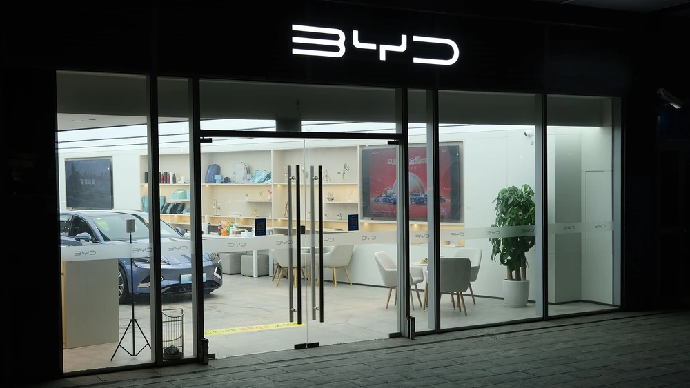 Fensterfront einer beleuchteten BYD Filiale mit Firmenlogo und Ausstellung