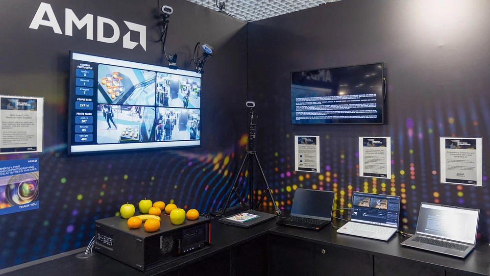 Messestand von Chipkonzern AMD mit Werbe-Bildschirmen an der Wand und ausgestellten Laptops