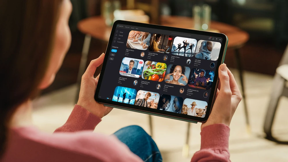 Netflix Oberfläche geöffnet auf Tablet gehalten von einer Frau auf dem Sofa