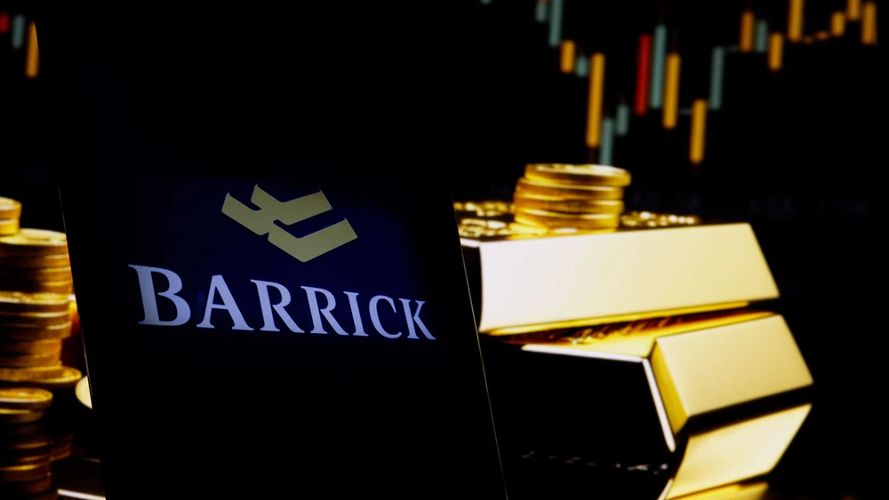 Barrick Gold Logo auf Smartphone vor Goldbarren in dunklem Licht