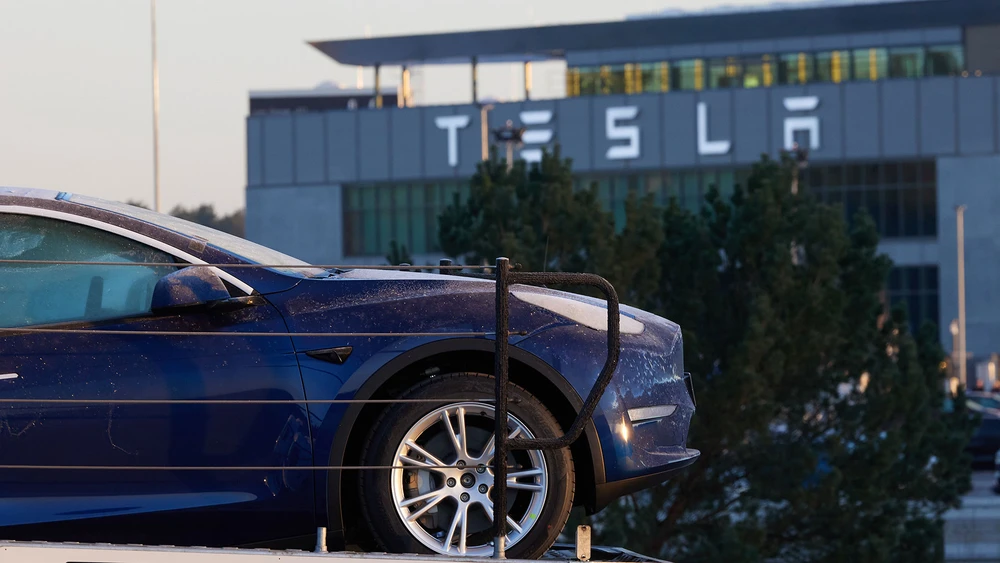 Ein Tesla parkt vor dem Tesla Firmengebäude mit Logo