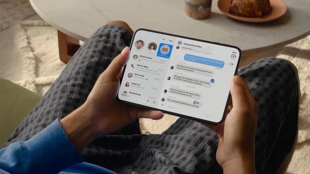 Blick auf ein Apple iPhone Duo in der Hand eines Mannes auf dem Sofa