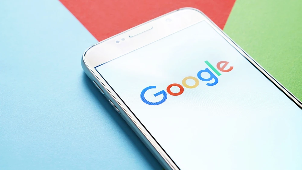 Google Logo auf Smartphone auf mehrfarbigem grafischen Hintergrund