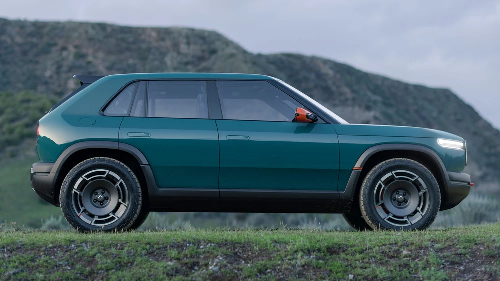 Rivian Modell Elliot Ross steht in Berglandschaft, Ansicht seitlich