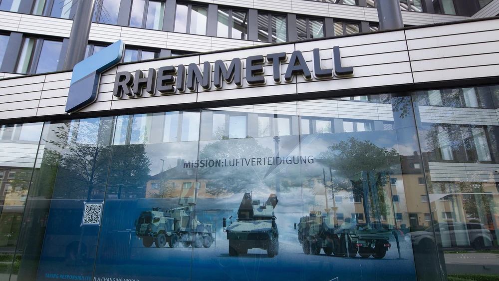 Eingang des Rheinmetall Firmensitzes mit Firmenlogo und Plakat mit Panzern