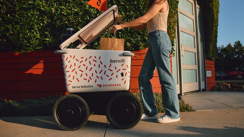 Lieferroboter von Serve Robotics, der für DoorDash im Einsatz ist, wird von einer Frau geöffnet